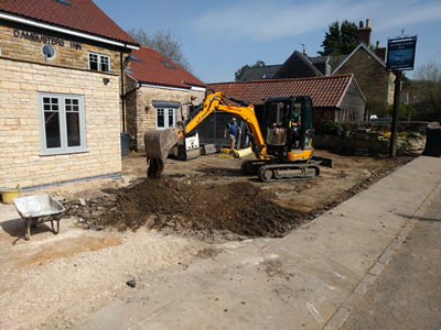 Ext. Day. Pub. The car parking area surface is being compacted in preparationg for resurfacing.