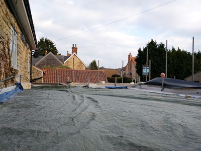 Ext. Day. Pub. The flat roof has been boarded and covered with waterproof membrane.